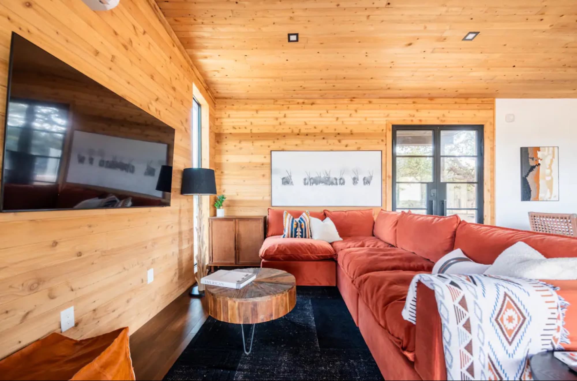 The living room with a rust sectional, wood walls and a fireplace